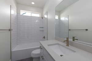 Full bathroom featuring vanity, tiled shower / bath combo, and toilet