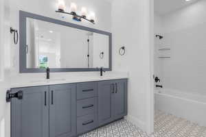 Bathroom with tiled shower / bath combo, vanity, and tile patterned floors