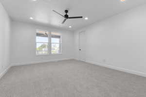 Empty room with ceiling fan, a textured ceiling, and light carpet