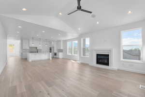 Unfurnished living room featuring ceiling fan, lofted ceiling, and light hardwood / wood-style floors