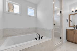 Bathroom featuring vanity and separate shower and tub