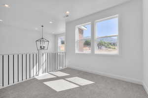 Carpeted spare room featuring a notable chandelier