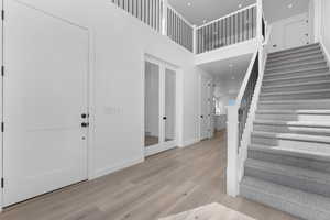 Entryway with light hardwood / wood-style flooring and a towering ceiling