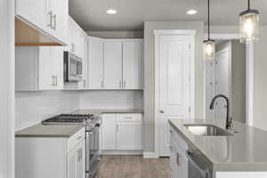 Kitchen with white cabinets, sink, light hardwood / wood-style flooring, and appliances with stainless steel finishes