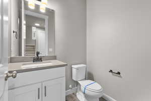 Bathroom with toilet, vanity, and wood-type flooring