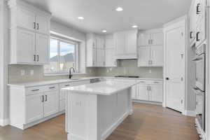 Kitchen with white cabinets, light hardwood / wood-style flooring, and a kitchen island