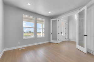 Unfurnished bedroom featuring light wood-type flooring and french doors