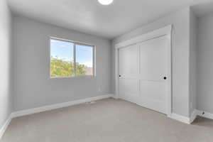 Unfurnished bedroom featuring light carpet and a closet