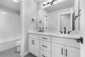 Full bathroom featuring toilet, tiled shower / bath combo, vanity, and tile patterned flooring