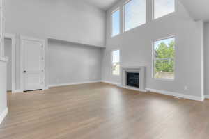 Unfurnished living room with light hardwood / wood-style flooring and a towering ceiling