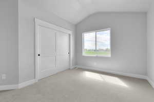 Unfurnished bedroom with lofted ceiling, light carpet, and a closet