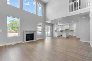 Unfurnished living room featuring a towering ceiling, a wealth of natural light, light hardwood / wood-style floors, and sink