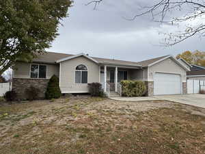 Single story home featuring covered porch, a garage, and a front lawn