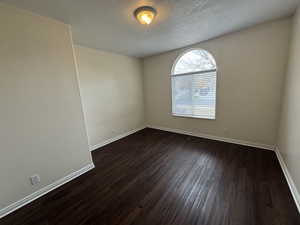 Unfurnished room featuring a textured ceiling and dark hardwood / wood-style floors