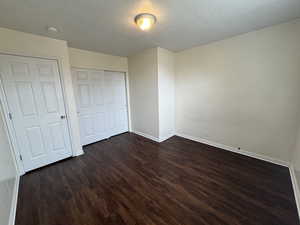 Unfurnished bedroom featuring dark wood-type flooring and a textured ceiling