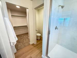 Bathroom featuring wood-type flooring, toilet, and a shower with door