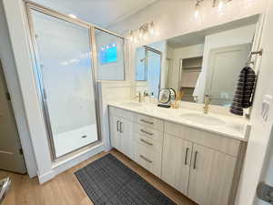 Bathroom featuring hardwood / wood-style floors, vanity, and an enclosed shower