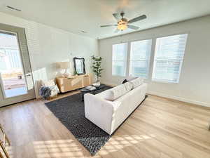 Living room with ceiling fan, plenty of natural light, and light wood-type flooring