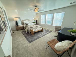 Carpeted bedroom featuring ceiling fan and a textured ceiling