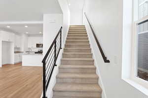 Stairway featuring wood-type flooring and sink