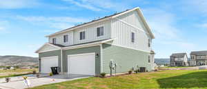 View of side of home with central air condition unit, a garage, a lawn, and a mountain view