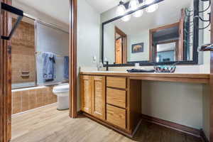 Full bathroom with vanity, wood-type flooring, tiled shower / bath, and toilet