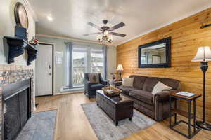 Living room with ornamental molding, a brick fireplace, baseboard heating, ceiling fan, and light hardwood / wood-style flooring