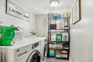 Washroom featuring washer and dryer and a textured ceiling