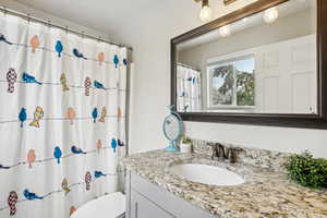 Bathroom with a shower with curtain, vanity, and toilet