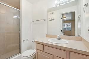 Bathroom with vanity, a shower with shower door, and toilet