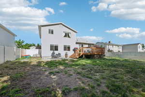 Rear view of house with a wooden deck and a yard