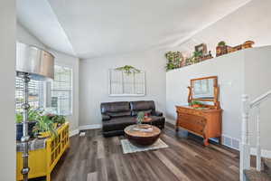 Living room featuring dark hardwood / wood-style flooring and lofted ceiling