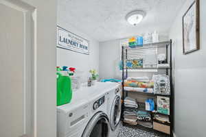 Laundry area featuring a textured ceiling and washer and dryer