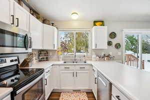 Kitchen with white cabinets, appliances with stainless steel finishes, plenty of natural light, and sink