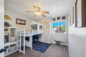 Bedroom with a textured ceiling, dark hardwood / wood-style floors, and ceiling fan