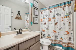 Bathroom featuring a shower with curtain, vanity, and toilet