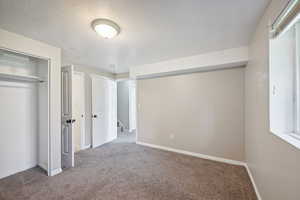 Unfurnished bedroom featuring carpet flooring, a textured ceiling, and a closet