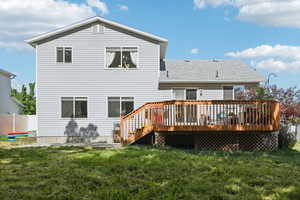 Rear view of property with a deck and a lawn