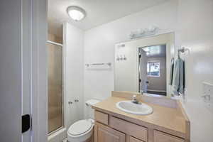 Bathroom featuring a shower with door, vanity, and toilet