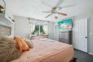 Bedroom featuring ceiling fan, dark hardwood / wood-style floors, and a textured ceiling