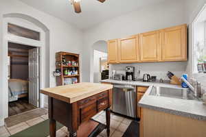 Kitchen with stainless steel dishwasher, ceiling fan, sink, light tile patterned floors, and light brown cabinets