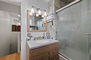 Bathroom featuring bath / shower combo with glass door, vanity, and wood-type flooring