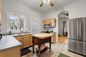 Kitchen with light brown cabinetry, sink, light tile patterned flooring, and appliances with stainless steel finishes