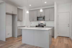 Kitchen featuring pendant lighting, a center island with sink, sink, and gas range