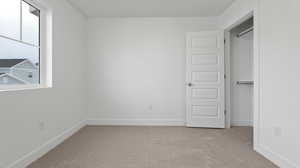 Unfurnished bedroom featuring light colored carpet and a closet