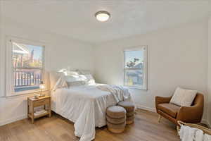 Bedroom with a textured ceiling and light hardwood / wood-style floors