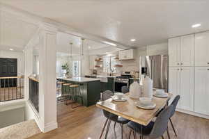 Dining area with light hardwood / wood-style floors, sink, and decorative columns