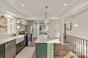 Kitchen featuring pendant lighting, white cabinetry, appliances with stainless steel finishes, and a healthy amount of sunlight