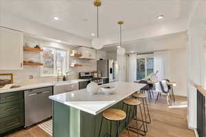 Kitchen featuring plenty of natural light, tasteful backsplash, white cabinetry, and stainless steel appliances