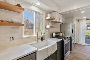 Kitchen with stainless steel appliances, tasteful backsplash, a healthy amount of sunlight, and light stone counters